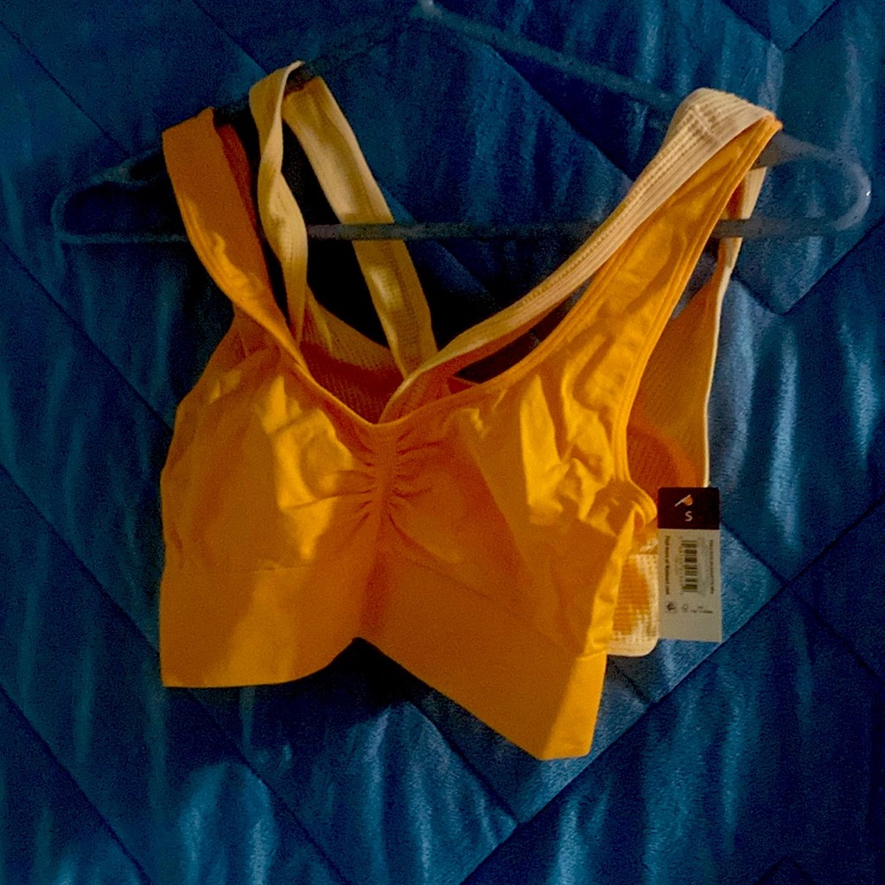 Never worn! Sports bra in light orange, size small.
